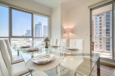 a dining room with a glass table and white chairs at Burj Residence 1, Downtown Dubai - Mint Stay in Dubai