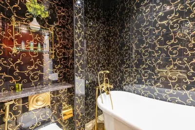 a bathroom with a tub and a black and gold wallpaper at StoneTree - Elegant Studio in Goldcrest View in Dubai