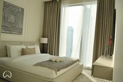 a bedroom with a large bed and a large window at Oraya - Modern Apt 5 min walk to Dubai Mall & Burj Views in Dubai