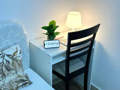 a desk with a lamp and a chair next to a bed at Charming Partition Room in Barsha Heights Near ICM in Dubai