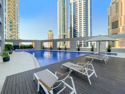 a patio with chairs and a pool with buildings at StoneTree - Fully Furnished 1BR in Dubai Marina in Dubai