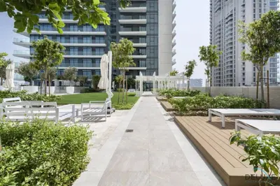 a park with white benches and trees and buildings at Inviting 1BR at Beach Vista Tower 1 Emaar Beachfront Dubai Marina by Deluxe Holiday Homes in Dubai