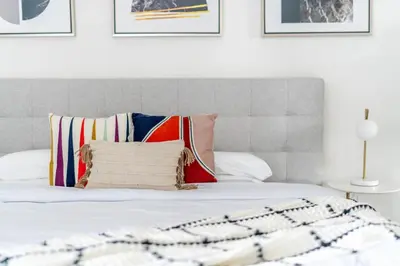 a white bed with a gray headboard and pillows at GuestReady - Mesmerizing views of the Burj Khalifa in Dubai