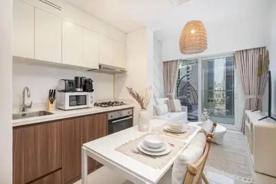 a kitchen and living room with a table and a microwave at Business Bay Bliss 1 bedroom apartment - Suiteable in Dubai