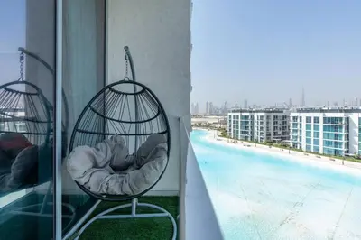 a bird cage sitting on a balcony next to a pool at One Bedroom - 10min from Burj Khalifa - Lagoon View in Dubai
