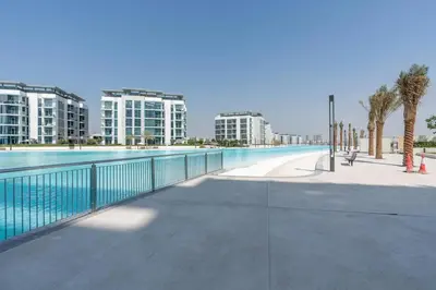 a large swimming pool with buildings in the background at One Bedroom - 10min from Burj Khalifa - Lagoon View in Dubai