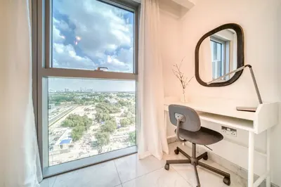 a desk with a mirror and a chair in front of a window at Central Park Towers, City View - DIFC - Mint Stay in Dubai
