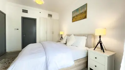 a white bedroom with a white bed and two lamps at Jumeriah Lake Tower (JLT)-(LAKE VIEW) in Dubai