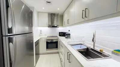 a kitchen with white cabinets and a stainless steel refrigerator at Jumeriah Lake Tower (JLT)-(LAKE VIEW) in Dubai