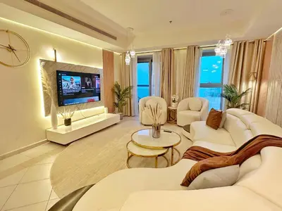a living room with white furniture and a flat screen tv at Life Above Clouds in Dubai