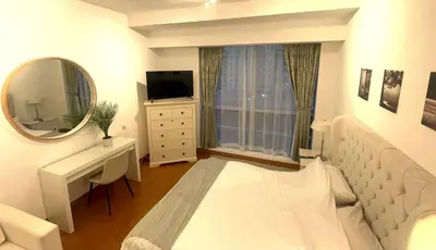 a white bedroom with a bed and a mirror at Marina view with Pool, Gym, Tennis Court, 5 mins to Beach in Dubai