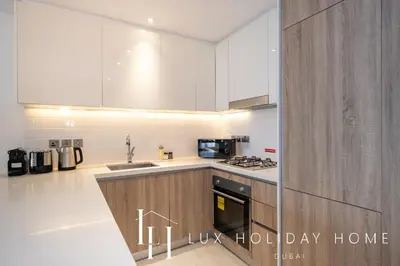 a kitchen with white cabinets and a stove top oven at LUX LIV Contemporary Full Marina View Suite in Dubai