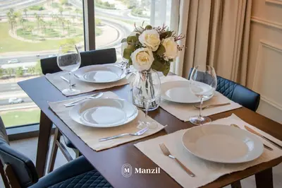 a table with plates and glasses and a vase with flowers at Azizi Farhad in Dubai