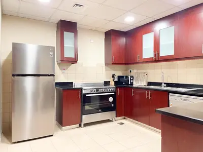 a kitchen with wooden cabinets and a stainless steel refrigerator at Spacious 4BR Apartment in JBR next to the Beach in Dubai