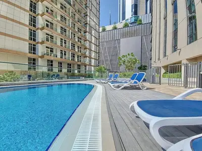a swimming pool with lounge chairs next to a building at Vacationer l Premium One Bed I Walk to Dubai Mall, Burj Khalifa I Dunya Tower Downtown in Dubai