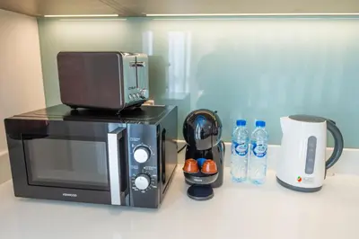 a microwave sitting on top of a counter next to bottles of water at Midtown Haven Cozy One Bed in Dubai in Dubai