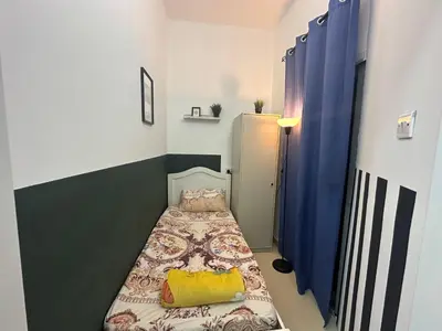 a small room with a bed and blue curtains at Private Partition Room Near Mashreq Metro in Dubai