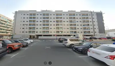 a parking lot with cars parked in front of a building at Private Partition Room Near Mashreq Metro in Dubai