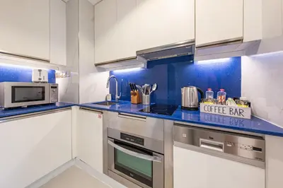 a kitchen with white cabinets and a blue counter top at Luxury Address Res Dubai Marina Studio in Dubai