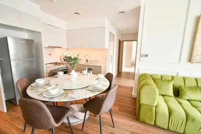 a kitchen and dining room with a table and a green couch at cinematic&Chic Burj Khalifa &Fountain View 2BR APT in Dubai