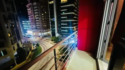 a view of a city at night from a balcony at Beautiful Partition Strip Room in Barsha Heights in Dubai