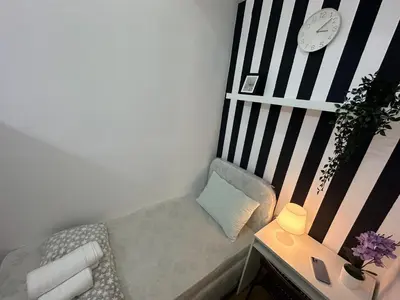 a small room with a chair and a clock on the wall at Beautiful Partition Strip Room in Barsha Heights in Dubai