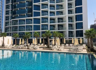a pool with chairs and umbrellas in front of a tall building at Phineek Elegant Studio Canal View Maison Prive Business Bay in Dubai