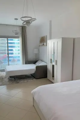 a white bedroom with two beds and a couch at Elite Studio at Dubai Marina in Dubai