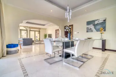 a dining room with a table and white chairs at Premier 6BR Villa with Assistant's Room and Private Pool in Frond E Palm Jumeirah by Deluxe Holiday Homes in Dubai