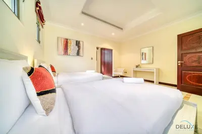 two beds in a room with two white beds at Premier 6BR Villa with Assistant's Room and Private Pool in Frond E Palm Jumeirah by Deluxe Holiday Homes in Dubai