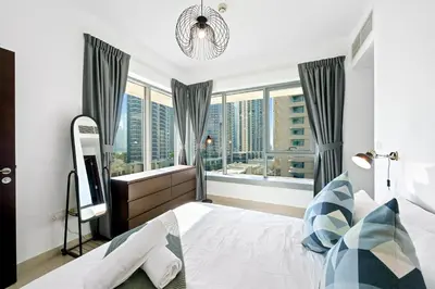 a bedroom with a bed and a large window at Cute 1 BR - Walk to Opera, Mall & Burj Khalifa in Dubai