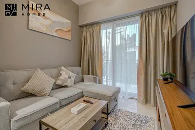 a living room with a couch and a large window at Mira Holiday Homes - Serviced apartment in Zada Tower in Dubai