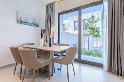 a dining room with a table and chairs and a window at Three Bedroom Villa with Maid Room in Tilal Al Ghaf by The S Holiday Homes in Dubai