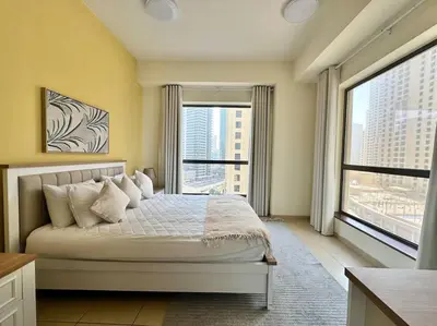 a bedroom with a large bed and large windows at Sun, Sand, and FUN - King Bed, Sofa Bed! Sleeps 4 in Dubai