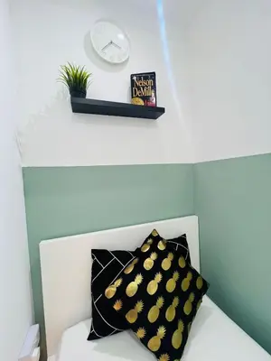a clock and a pillow on a white couch at Flexible Small Partition Room Near MOE in Dubai