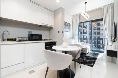 a kitchen with white cabinets and a table and chairs at Stylish Apartment in Dubai
