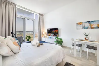 a white bedroom with a desk and a bed at Cozy Studio 29th Floor, Bloom Towers Marina View in Dubai