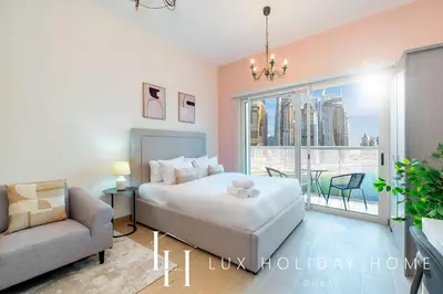 a bedroom with a bed and a couch and a window at LUX The Marina View Suite 2 in Dubai