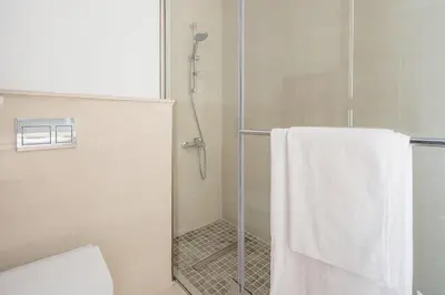 a bathroom with a shower with a white towel at Frank Porter - Bluebell Residence JVC in Dubai