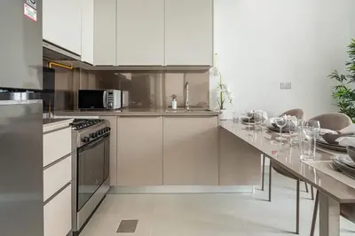 a kitchen with white cabinets and a table with wine glasses at Frank Porter - Bluebell Residence JVC in Dubai