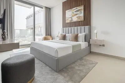 a bedroom with a large bed and a chair at Frank Porter - Bluebell Residence JVC in Dubai