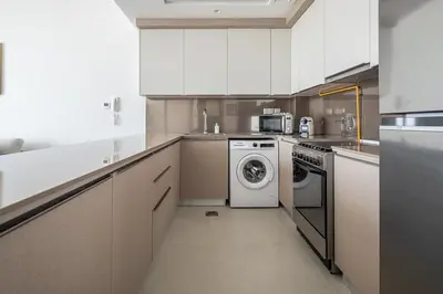 a kitchen with white cabinets and a washer and dryer at Frank Porter - Bluebell Residence JVC in Dubai