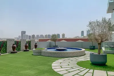 a garden with a fountain in the middle of a lawn at Frank Porter - Bluebell Residence JVC in Dubai
