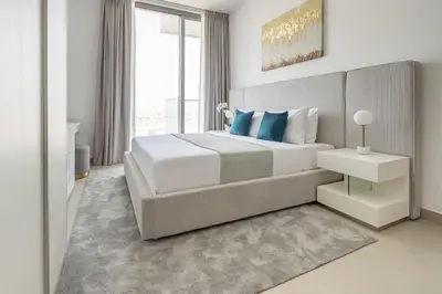 a white bedroom with a large bed with blue pillows at Frank Porter - Bluebell Residence JVC in Dubai