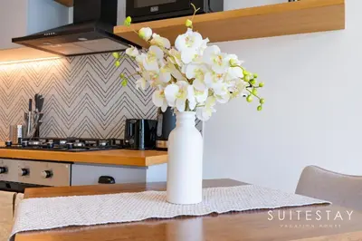 a white vase filled with white flowers on a table at Chic Bright One Bedroom Suite in Dubai