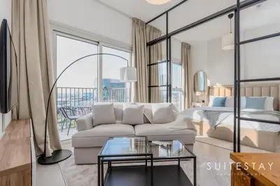 a living room with a couch and a bed at Chic Bright One Bedroom Suite in Dubai
