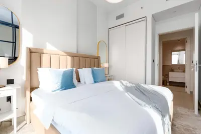 a bedroom with a large white bed with blue pillows at Chic Bright One Bedroom Suite in Dubai