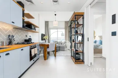 a kitchen with white cabinets and a dining room at Chic Bright One Bedroom Suite in Dubai
