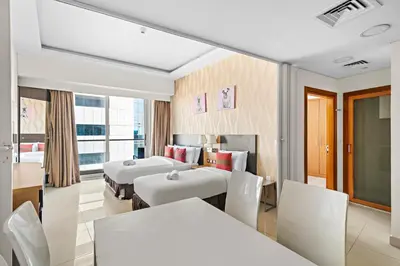 a hotel room with two beds and a table and chairs at Great 2BR APT Ocean Heights in Dubai