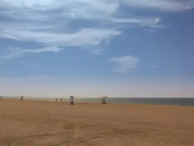 a beach with people and an umbrella and the ocean at Beautiful 1 bedroom in Port De La Mer in Dubai